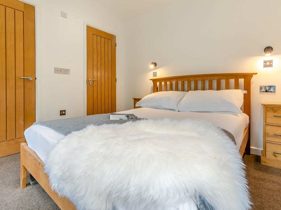 A bedroom with a bed and wooden furniture at Treehouse Spa in Perranporth