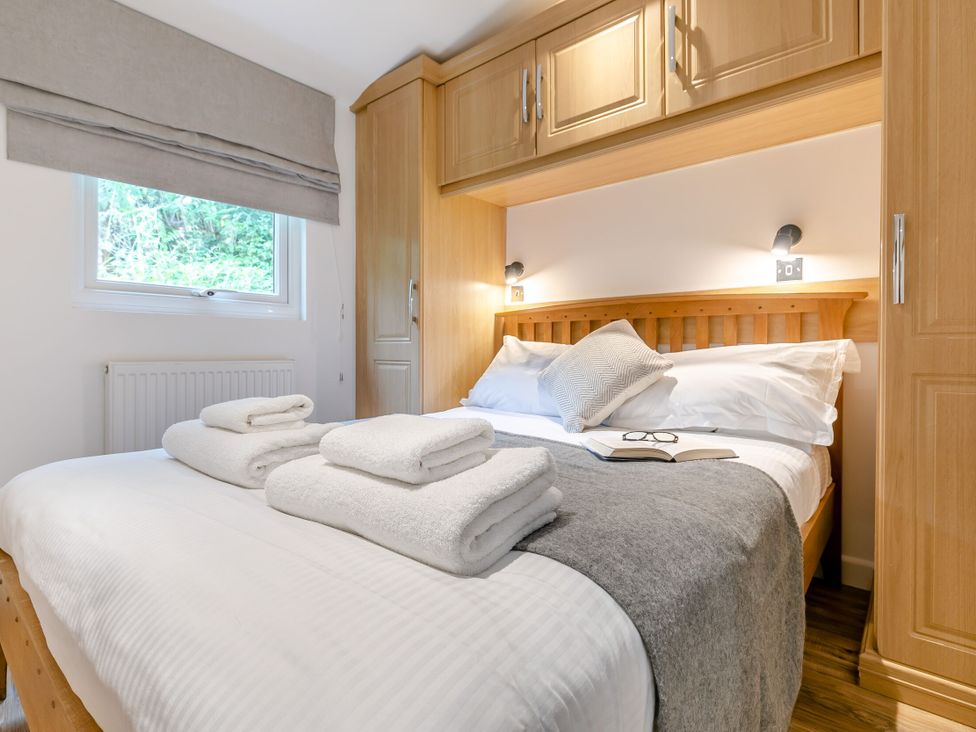 A bedroom with a bed, towels, and wardrobe at Morva Spa Pet in Perranporth