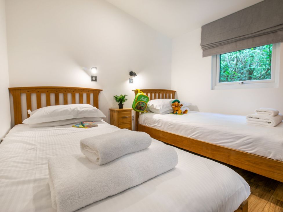 A bedroom with two beds and a nightstand at Morva Spa Pet in Perranporth