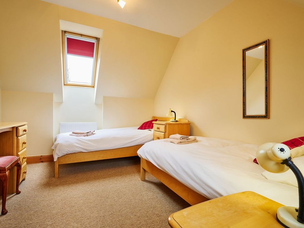 A bedroom with two beds and a desk at Hazel Lodge in Blairgowrie