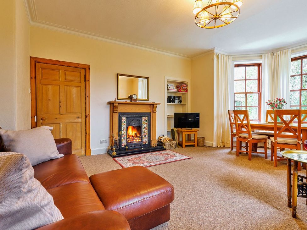A living room with a fireplace and dining area at West Lodge in Kirriemuir