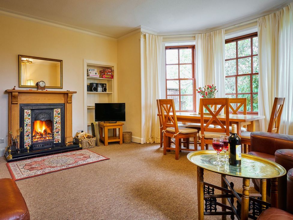 A living room with a fireplace and dining area at West Lodge in Kirriemuir
