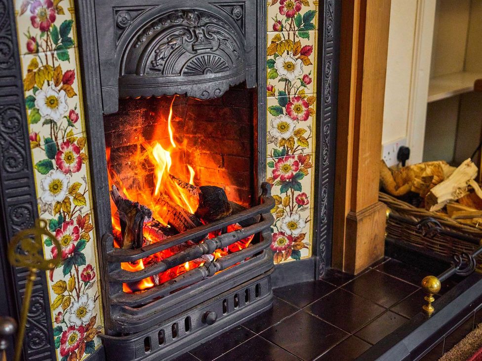 A fireplace with flames and logs at West Lodge Kirriemuir