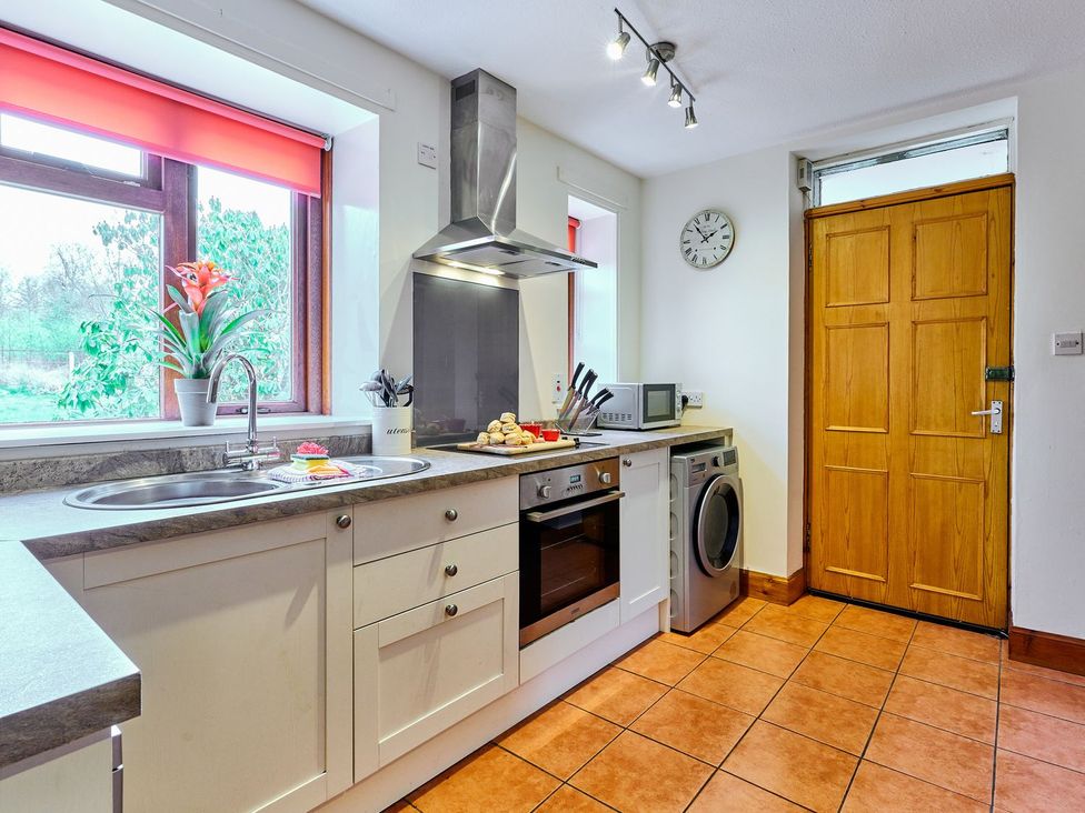 A kitchen with a sink, oven, microwave and washing machine at West Lodge in Kirriemuir
