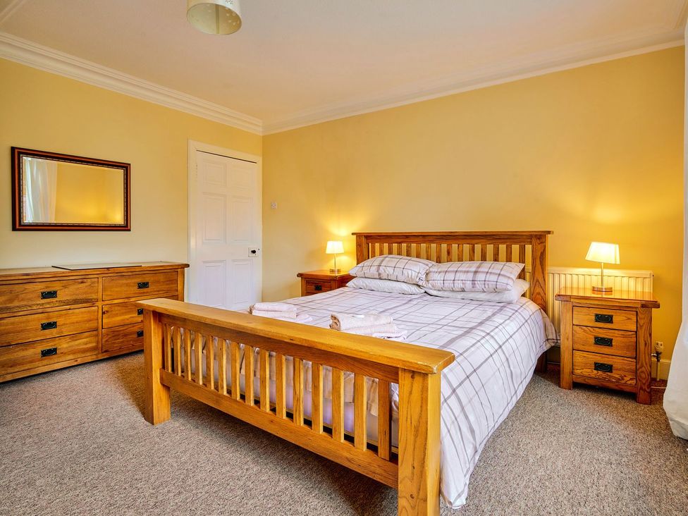 A bedroom with a wooden bed and dresser at West Lodge in Kirriemuir