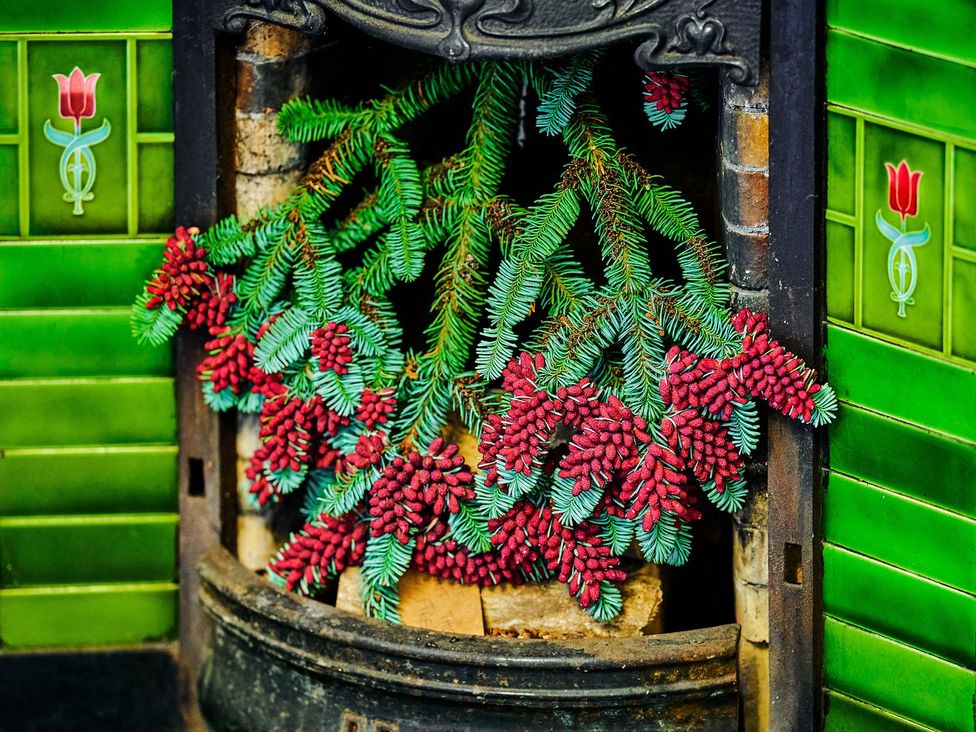 A fireplace with pine cones and wood logs at West Lodge in Kirriemuir