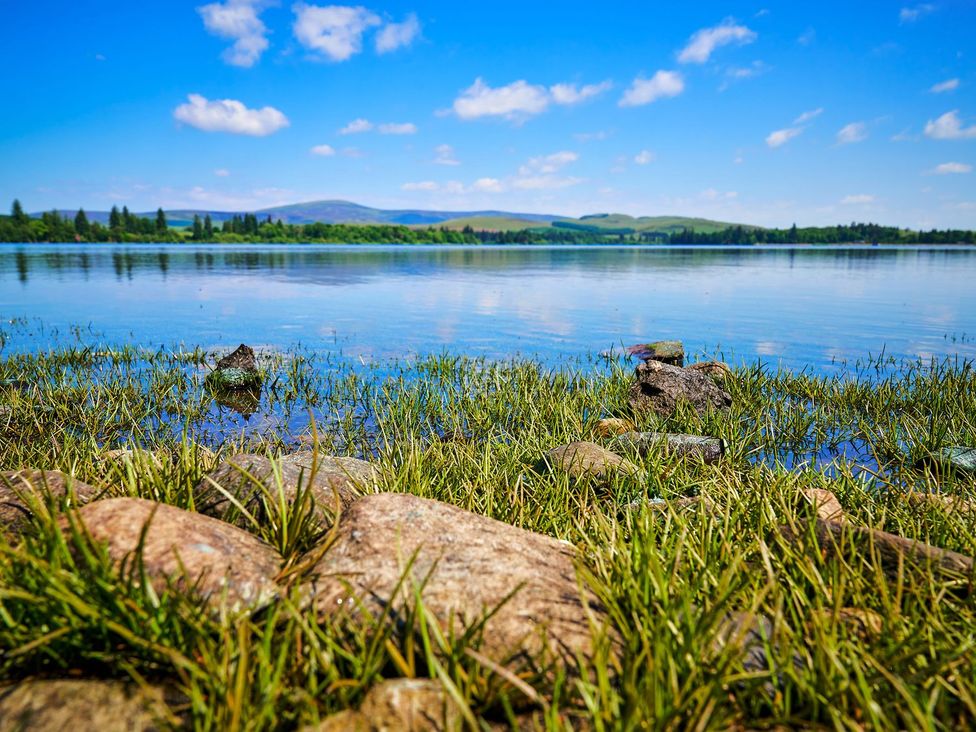 A lake surrounded by grass and rocks at West Lodge in Kirriemuir