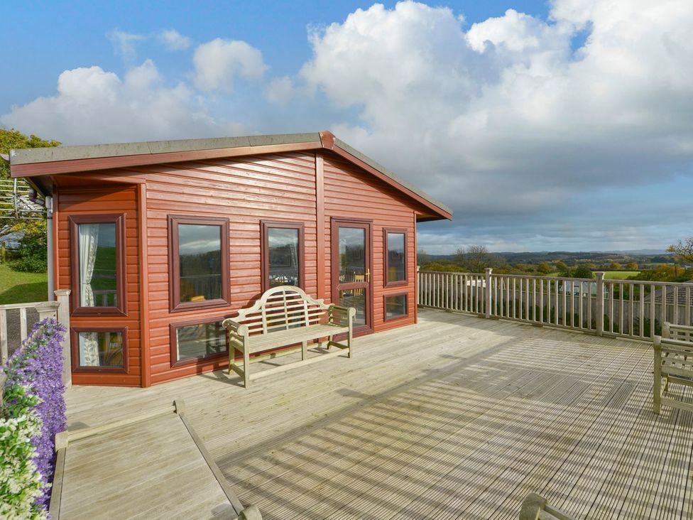 A log cabin with decking and a bench at Dartmoor View in Exeter