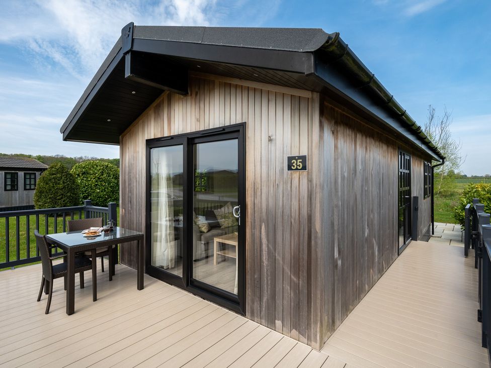 A wooden cabin with a table and chairs outside at Stokesley (Pet) Great Ayton