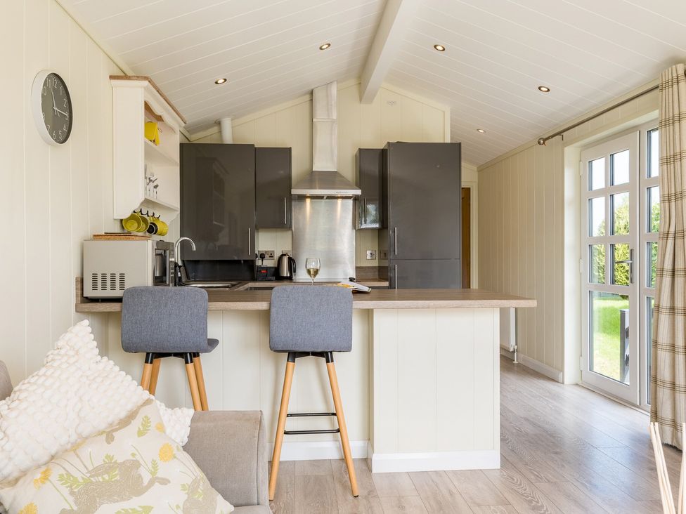 A kitchen with bar stools and modern appliances at Stokesley (Pet) Great Ayton