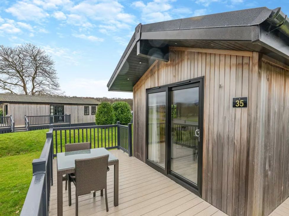 An outdoor area with a lodge, table and chairs at Stokesley (Pet) Great Ayton