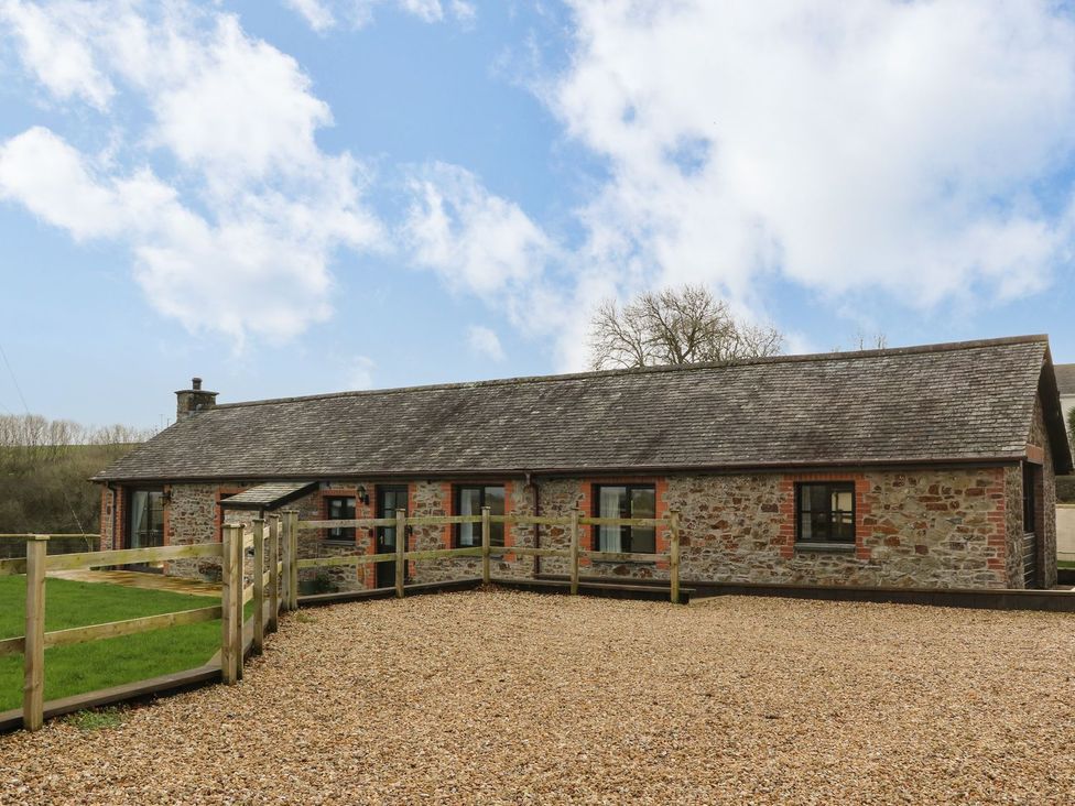 A stone building with a fence and gravel area at Long Linney in Bideford