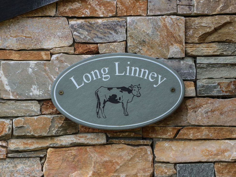 A sign with the name Long Linney and a cow illustration on a stone wall at Long Linney in Bideford