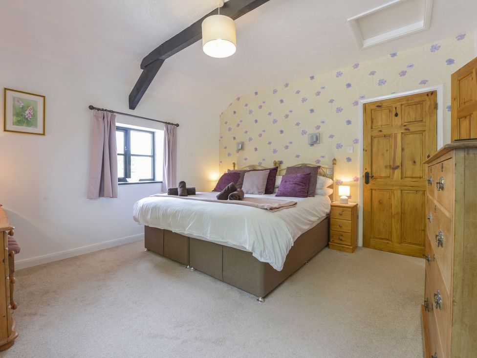 A bedroom with a large bed and wooden furniture at Long Linney in Bideford