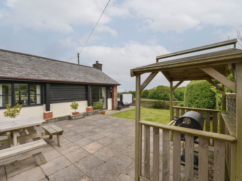 An outdoor area with a deck, table, and grill at Long Linney in Bideford