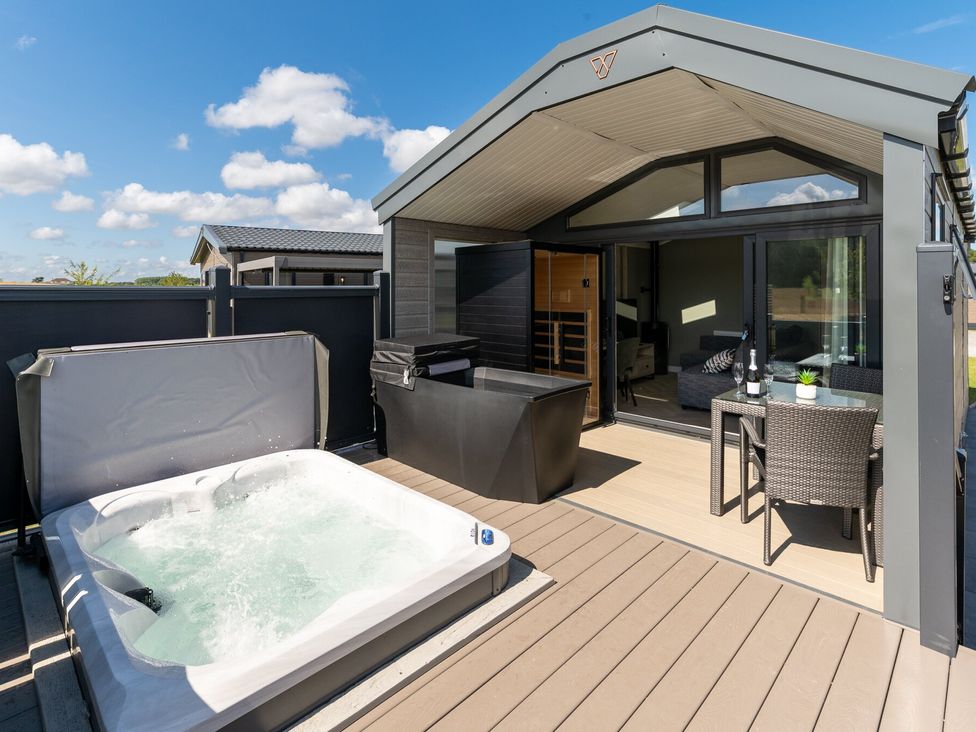 An outdoor area with a hot tub and seating at The Oasis in Great Ayton