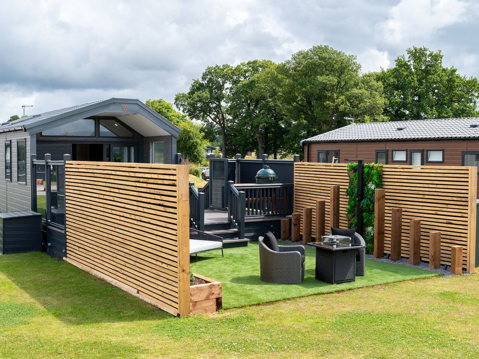 An outdoor area with a house, deck, chairs, and table at The Oasis in Great Ayton