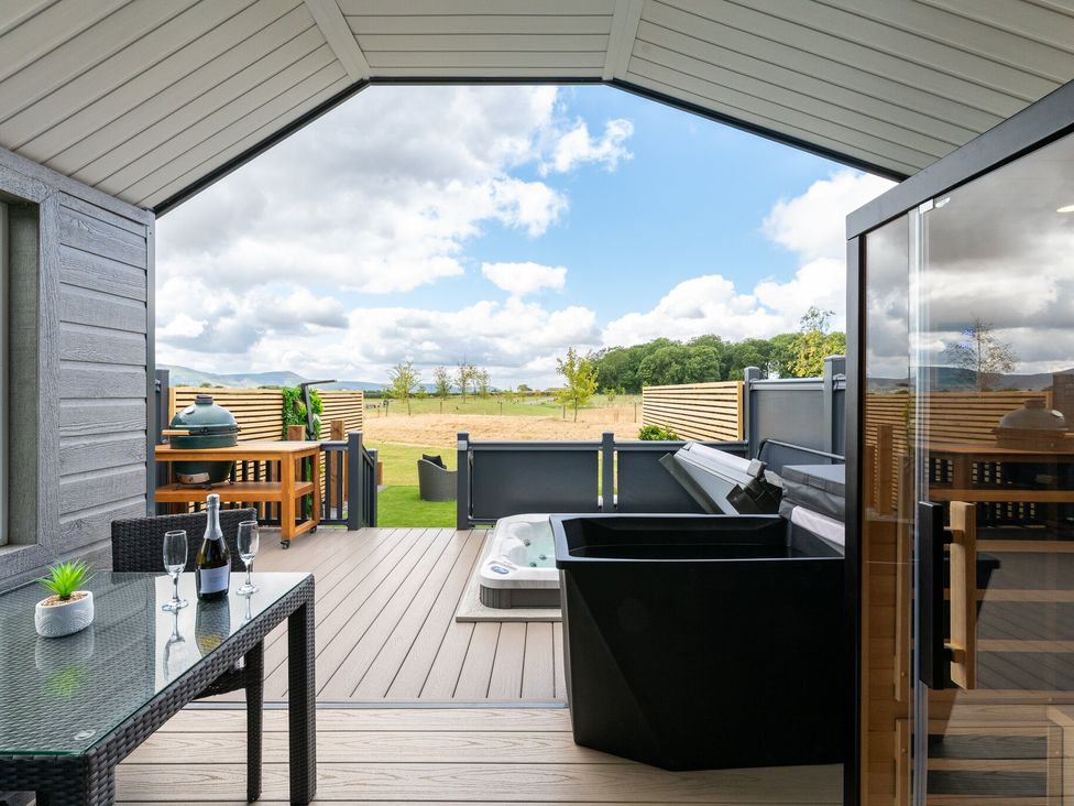 An outdoor patio with a hot tub and seating area at The Oasis in Great Ayton