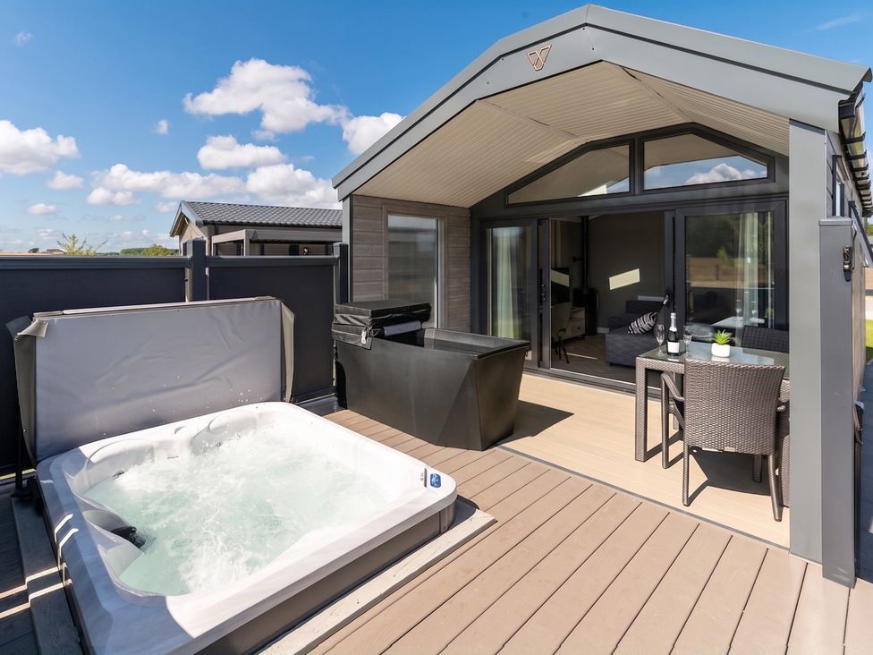 An outdoor patio with a hot tub and seating area at The Oasis in Great Ayton