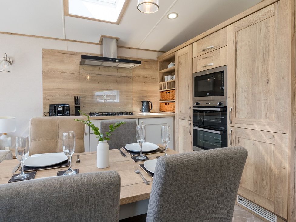 A kitchen with wooden cabinets and dining area at Leven (Pet) Great Ayton