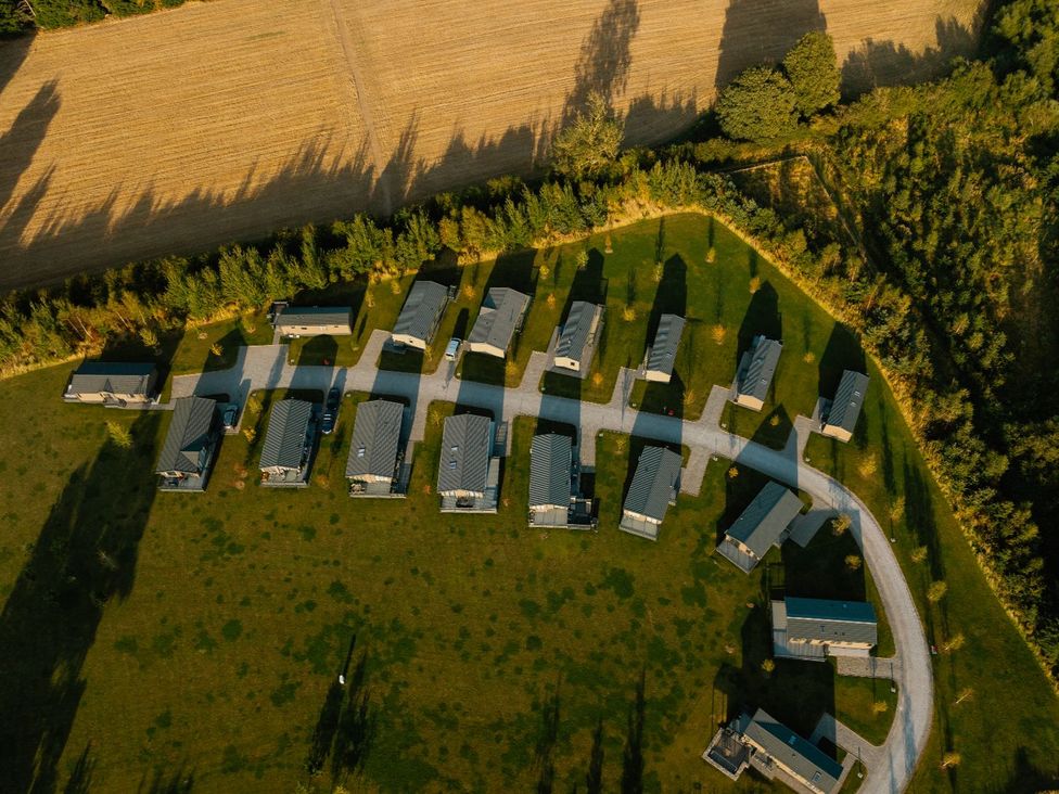 An aerial view of cabins and a gravel road surrounded by trees and a field at Roseberry (Pet) Great Ayton