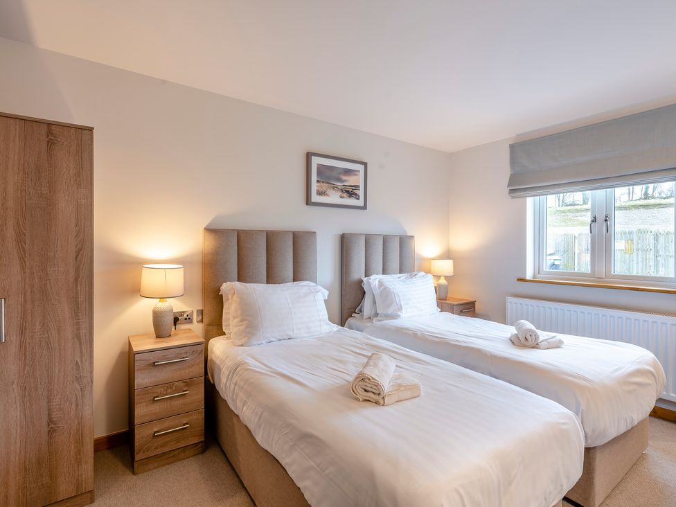 A bedroom with twin beds, bedside tables and a wardrobe at Tranquillity 3 (Pet) in Carnforth