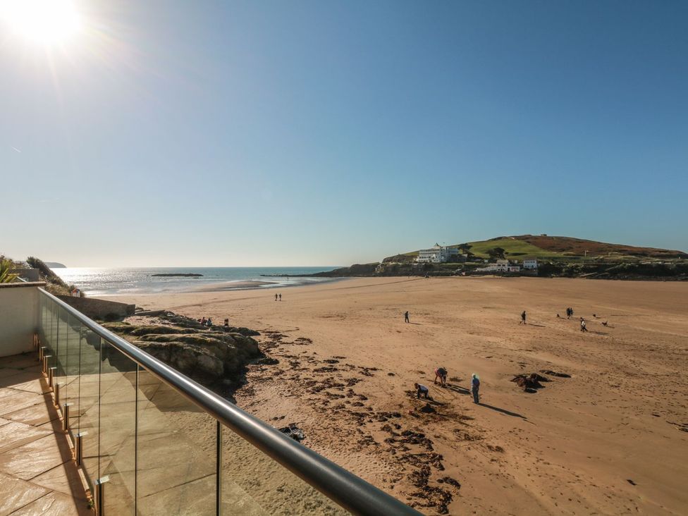A beach view with people walking and a hill at 2 Burgh Island Causeway in Kingsbridge