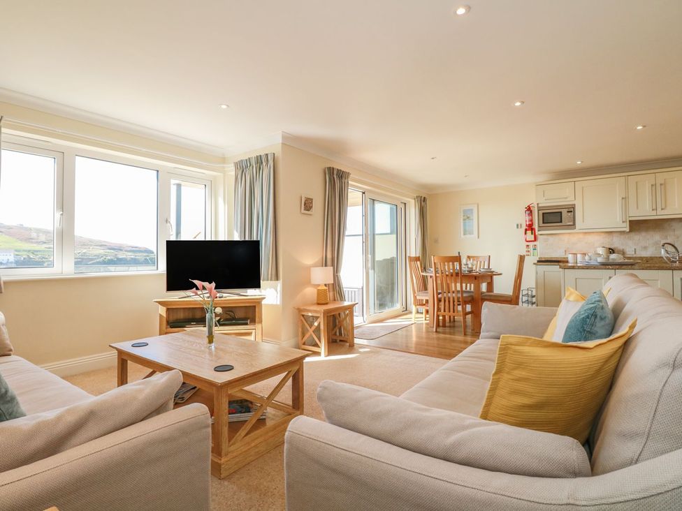 A living room with sofa and dining area at 2 Burgh Island Causeway in Kingsbridge