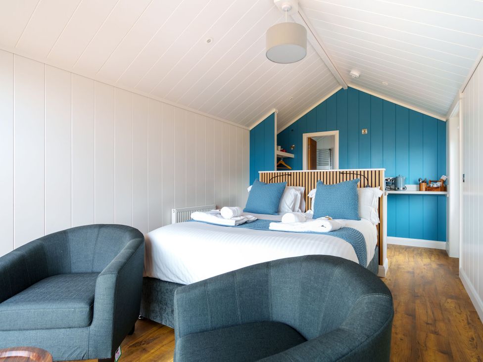 A bedroom with a bed and armchairs at The Grays in North Berwick