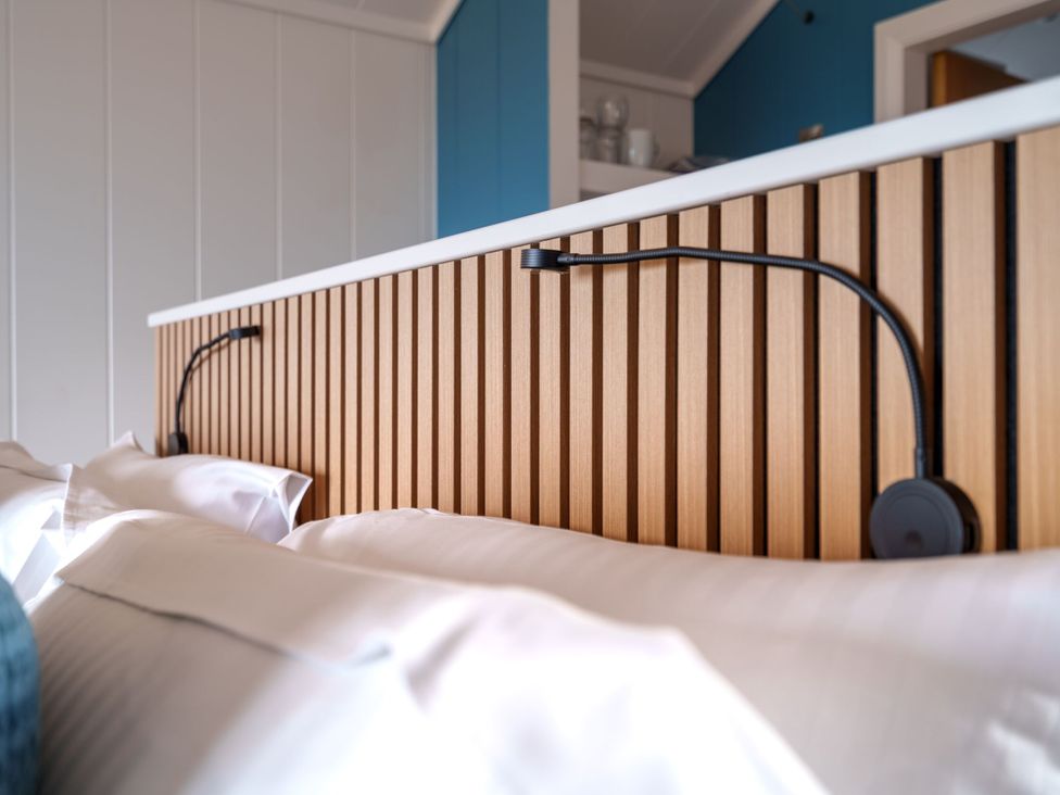 A bed with a wooden headboard and lamps at The Grays in North Berwick