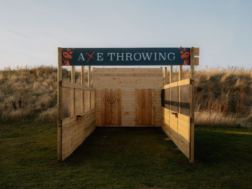An axe throwing booth with wooden targets and a sign at The Grays in North Berwick