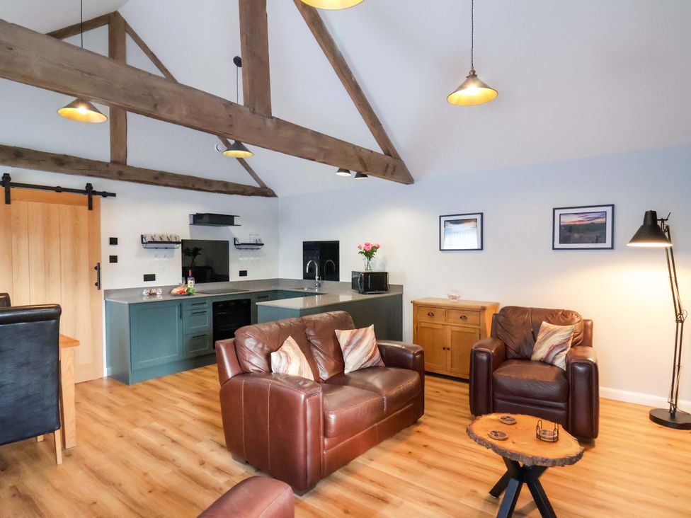 A living room with a sofa and kitchen area at The Homestead in Moorsholm