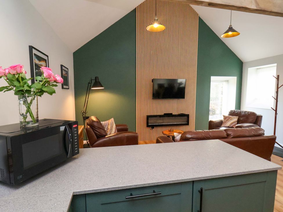 A living room with a television, sofa, and microwave at The Homestead in Moorsholm