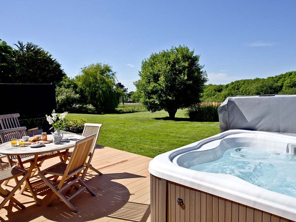 A garden with a hot tub and dining table at 4C2 Summerleaze Garden Cottage 2 Spa Bude
