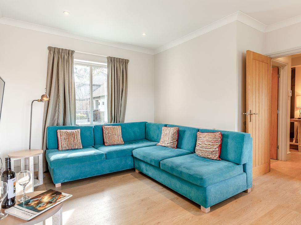 A living room with a blue sofa and a table at 4C2 Summerleaze Garden Cottage 2 Spa in Bude