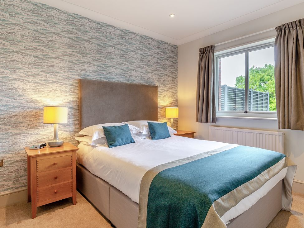 A bedroom with a bed and nightstand at 4C2 Summerleaze Garden Cottage 2 Spa in Bude