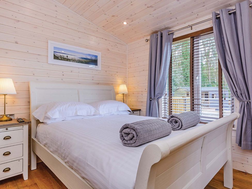 A bedroom with a bed and bedside table at Hurricane Lodge in Fair Oak