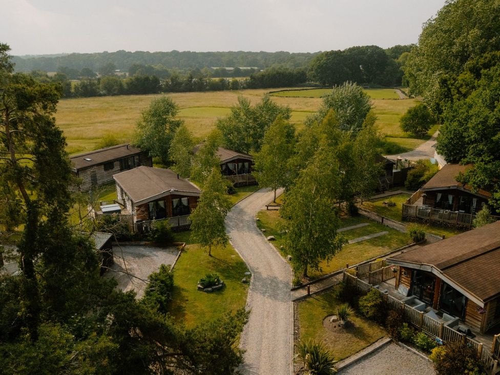 A view of cabins with trees and a gravel path at Hurricane Lodge in Fair Oak