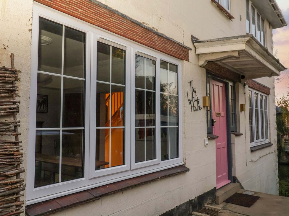 An exterior view of The White House in Norwich showing windows and a pink door