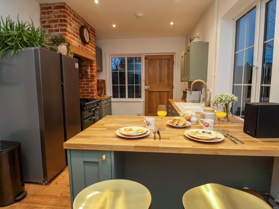A kitchen with a wooden island and seating at The White House in Norwich