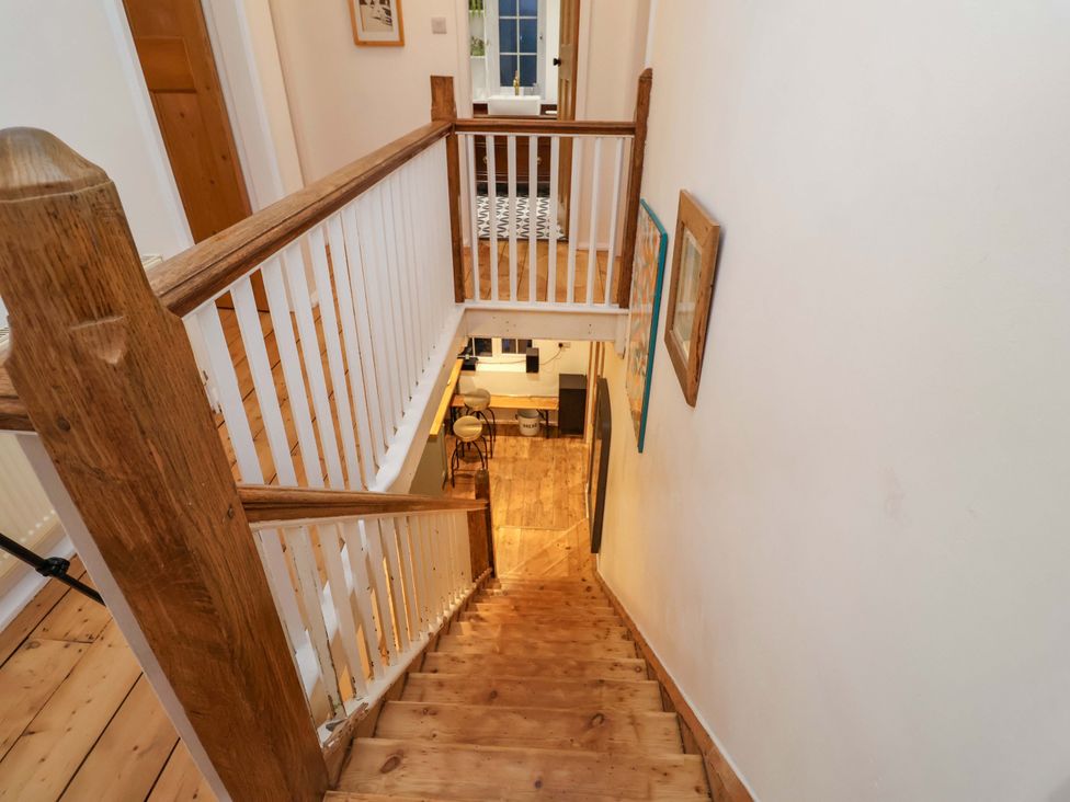 A staircase leading down with a railing and light at The White House in Norwich
