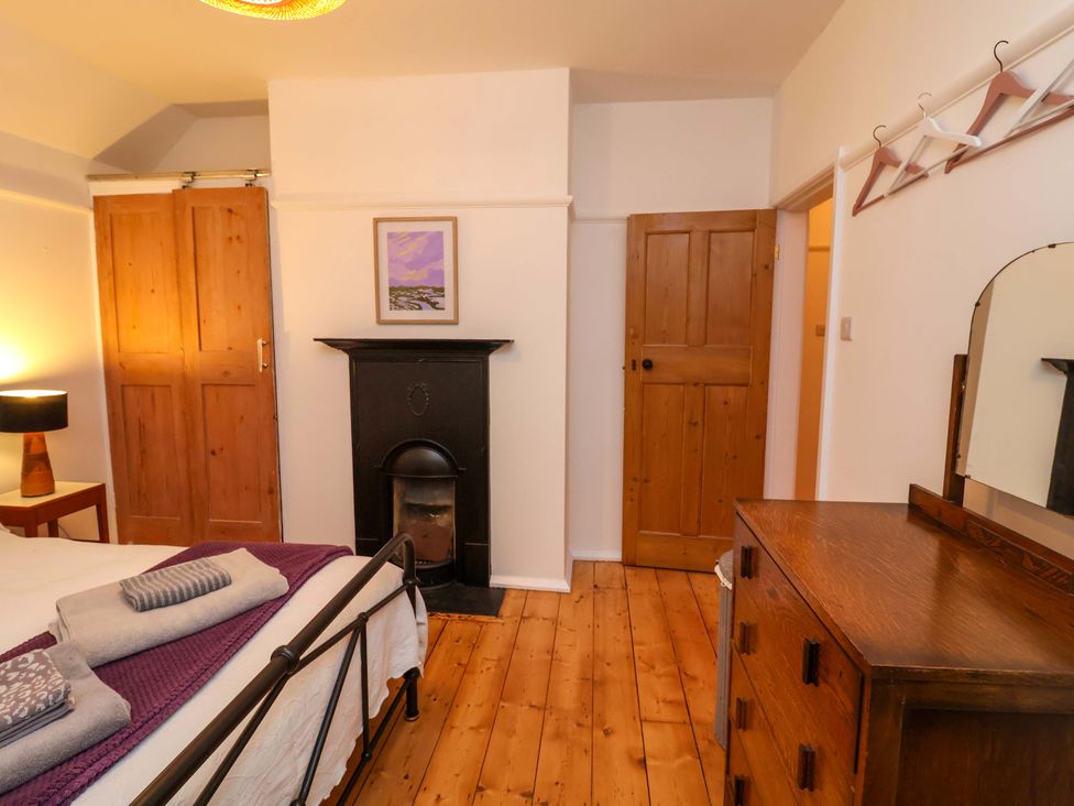 A bedroom with a bed, lamp, dresser and fireplace at The White House in Norwich