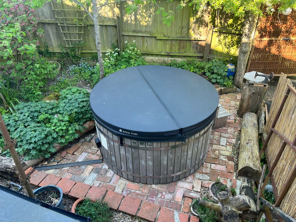 A hot tub in a garden with brick pathway at The White House in Bracondale