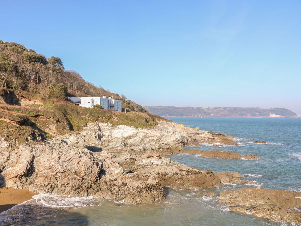 A coastline with rocks and a building at The Old Signal House in Torpoint
