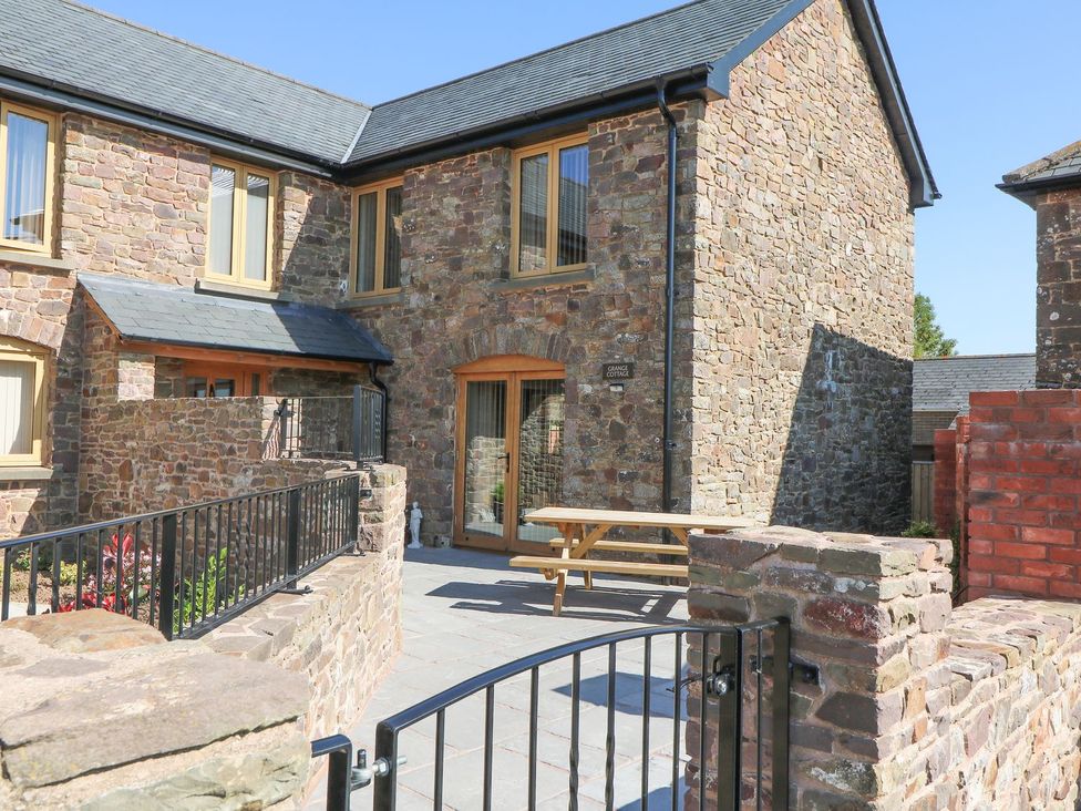 An outdoor area with a table and stone walls at Grange Cottage in Crediton