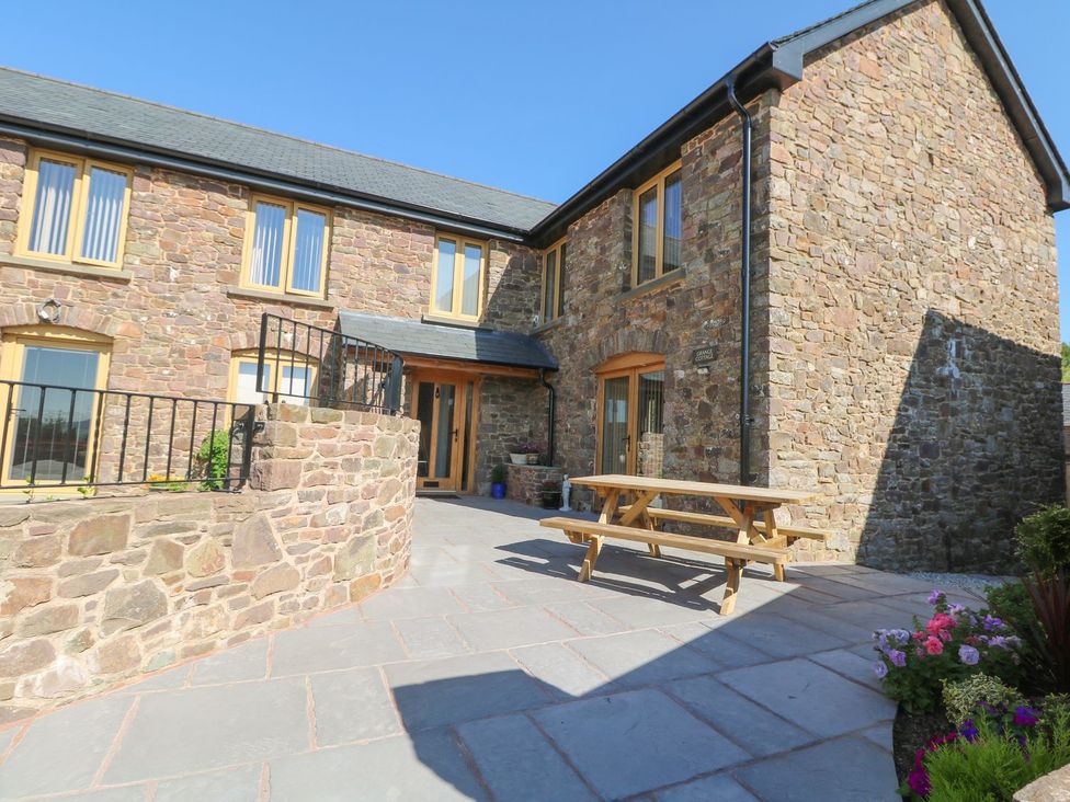 An outdoor area with a stone wall and bench at Grange Cottage in Crediton