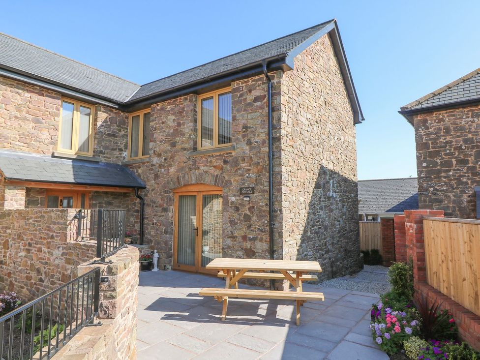 An outdoor area with a stone building and a picnic table at Grange Cottage in Crediton