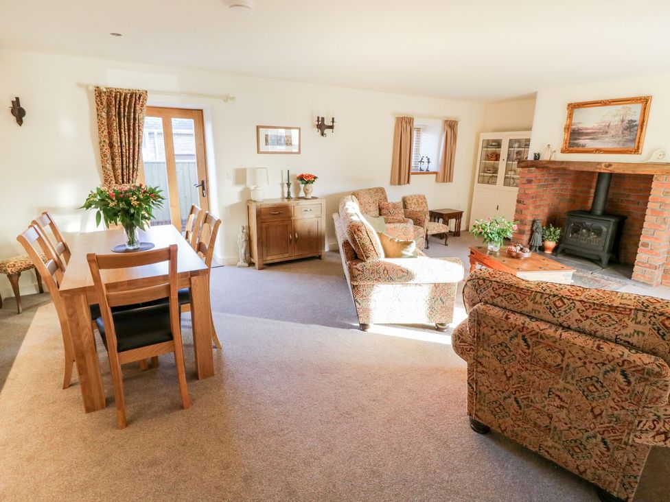 A living room with dining area and fireplace at Grange Cottage in Crediton