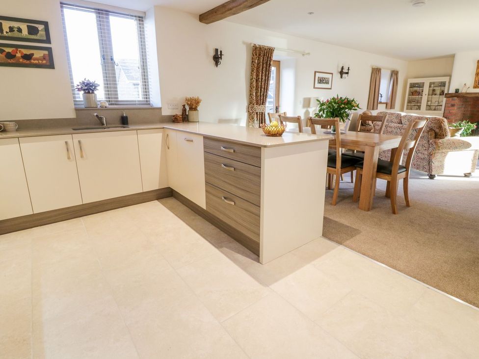 A kitchen with cabinets and a dining area at Grange Cottage in Crediton