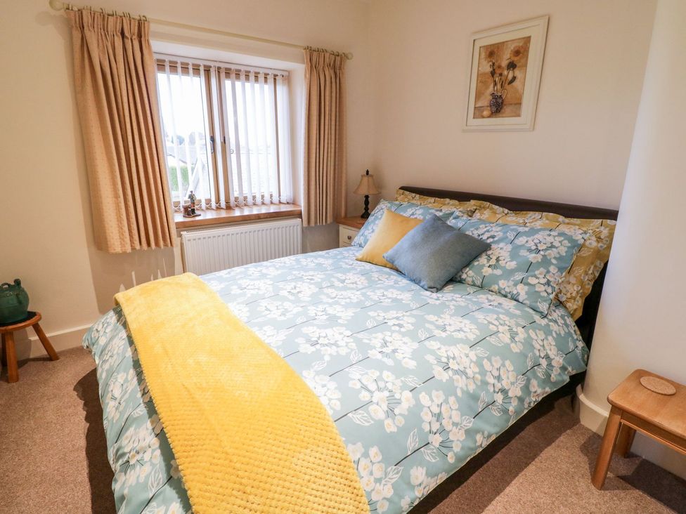 A bedroom with a bed and window at Grange Cottage in Crediton